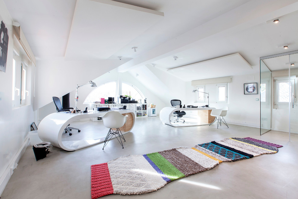 Modelo de despacho contemporáneo extra grande sin chimenea con escritorio independiente, suelo de cemento y paredes blancas