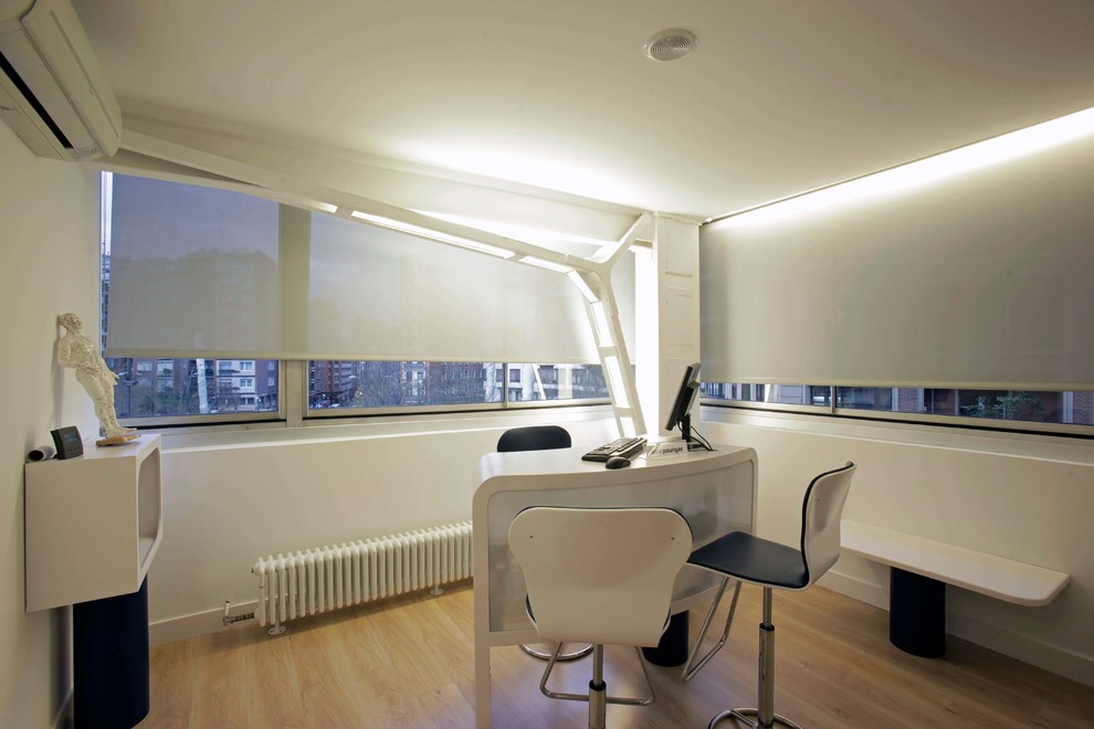 Идея дизайна: рабочее место среднего размера в современном стиле с белыми стенами, паркетным полом среднего тона и отдельно стоящим рабочим столом без камина