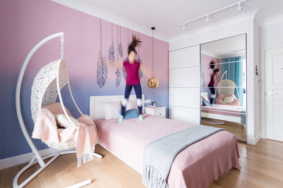 Modelo de dormitorio infantil actual grande con paredes rosas, suelo de madera en tonos medios y suelo beige