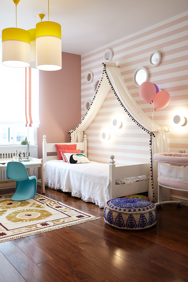 Immagine di una cameretta per bambini da 4 a 10 anni tradizionale di medie dimensioni con pareti rosa, pavimento marrone e parquet scuro