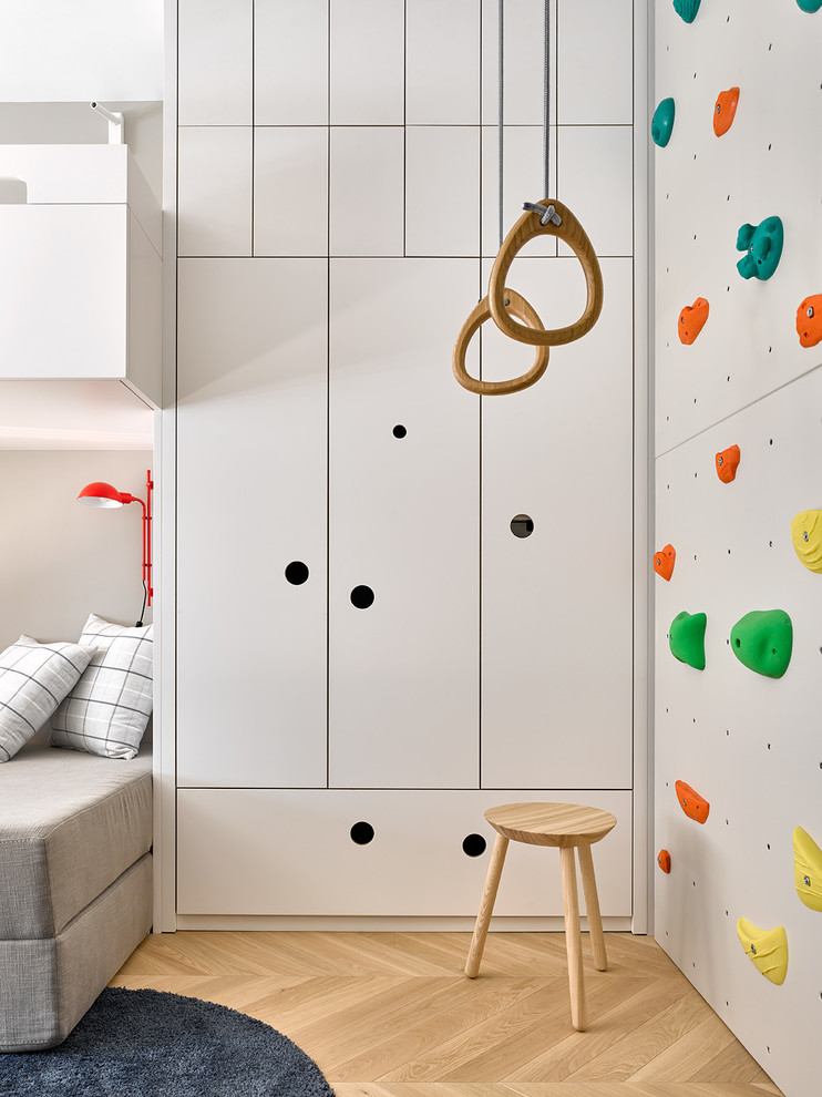 This is an example of a medium sized contemporary gender neutral children’s room in Moscow with grey walls and light hardwood flooring.