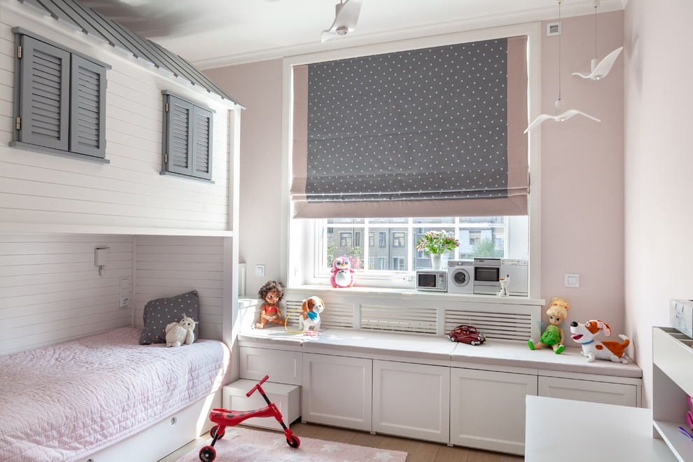Inredning av ett klassiskt flickrum kombinerat med sovrum, med rosa väggar, mellanmörkt trägolv och brunt golv