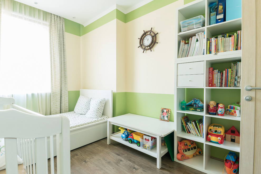 Idee per una piccola cameretta per bambini da 1 a 3 anni contemporanea con pareti verdi, pavimento in laminato e pavimento marrone