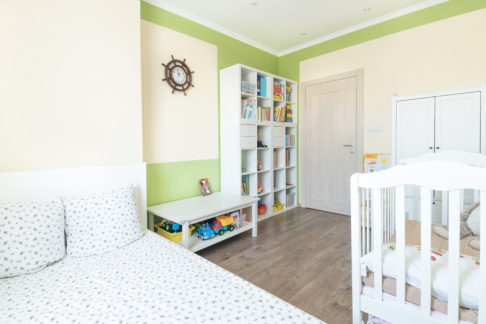 Aménagement d'une petite chambre d'enfant de 1 à 3 ans contemporaine avec un mur vert, sol en stratifié et un sol marron.