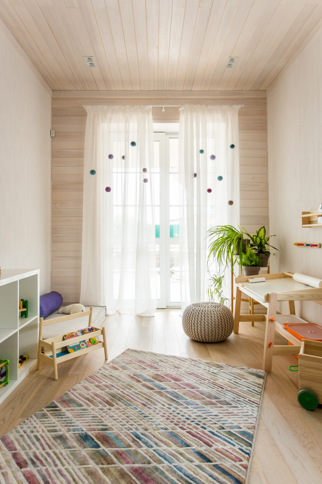 Modern inredning av ett barnrum, med beige väggar, ljust trägolv och beiget golv