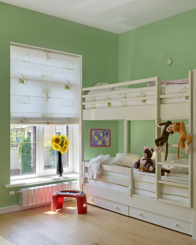 This is an example of a classic gender neutral kids' bedroom in Other with green walls, light hardwood flooring and beige floors.