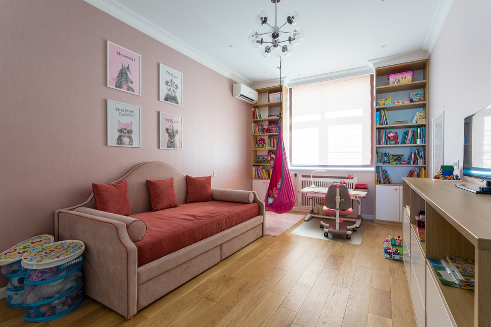 Esempio di una cameretta per bambini da 4 a 10 anni scandinava di medie dimensioni con pareti rosa, pavimento in legno massello medio e pavimento marrone