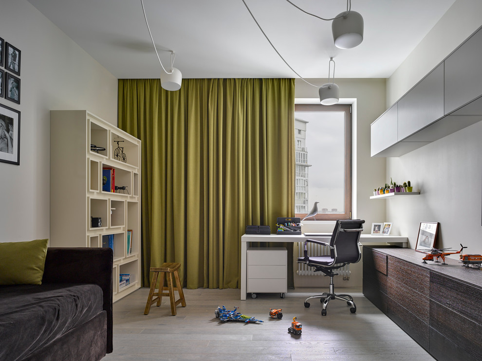 Imagen de habitación infantil unisex contemporánea con escritorio, paredes blancas y suelo de madera clara