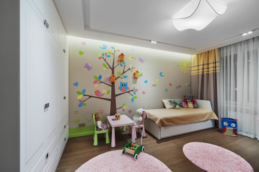 Immagine di una cameretta per bambini da 1 a 3 anni contemporanea di medie dimensioni con pareti beige, pavimento in legno massello medio e pavimento marrone