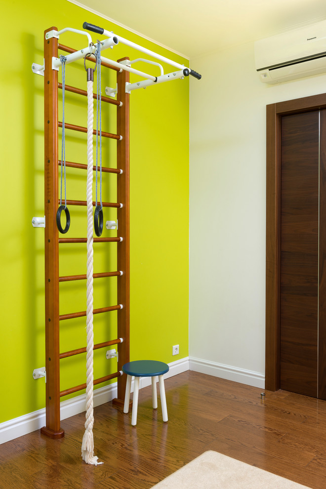 Aménagement d'une chambre d'enfant de 4 à 10 ans contemporaine avec un mur vert et un sol en bois brun.