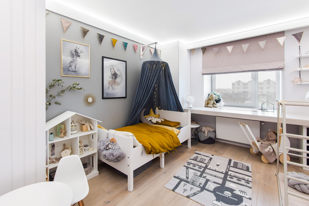Photo of a scandi toddler’s room for girls in Saint Petersburg with grey walls and light hardwood flooring.