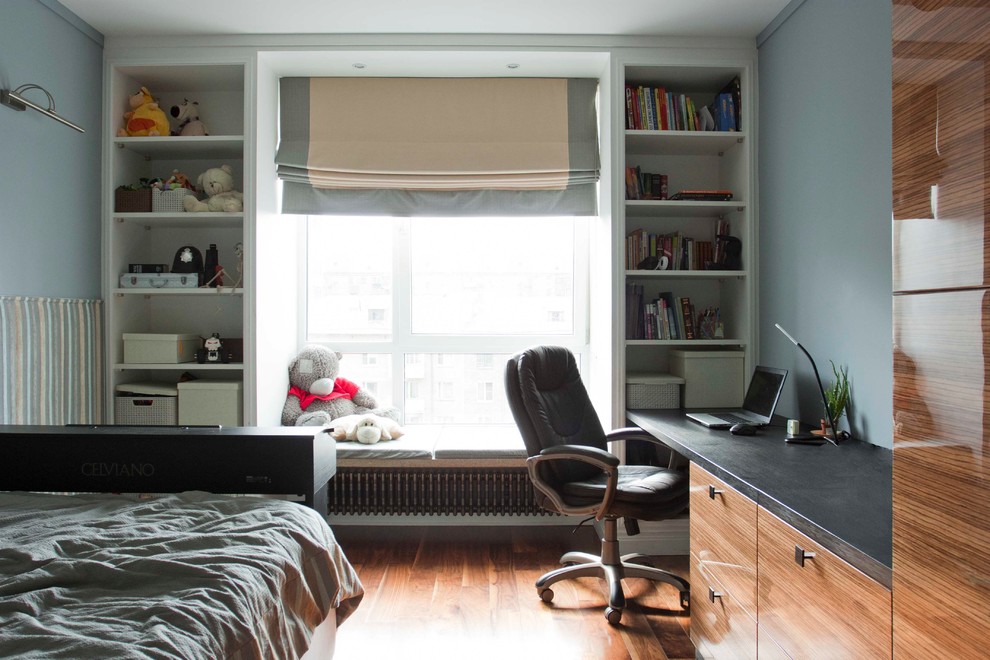 Cette photo montre une chambre de garçon tendance avec un bureau, un mur bleu et un sol en bois brun.