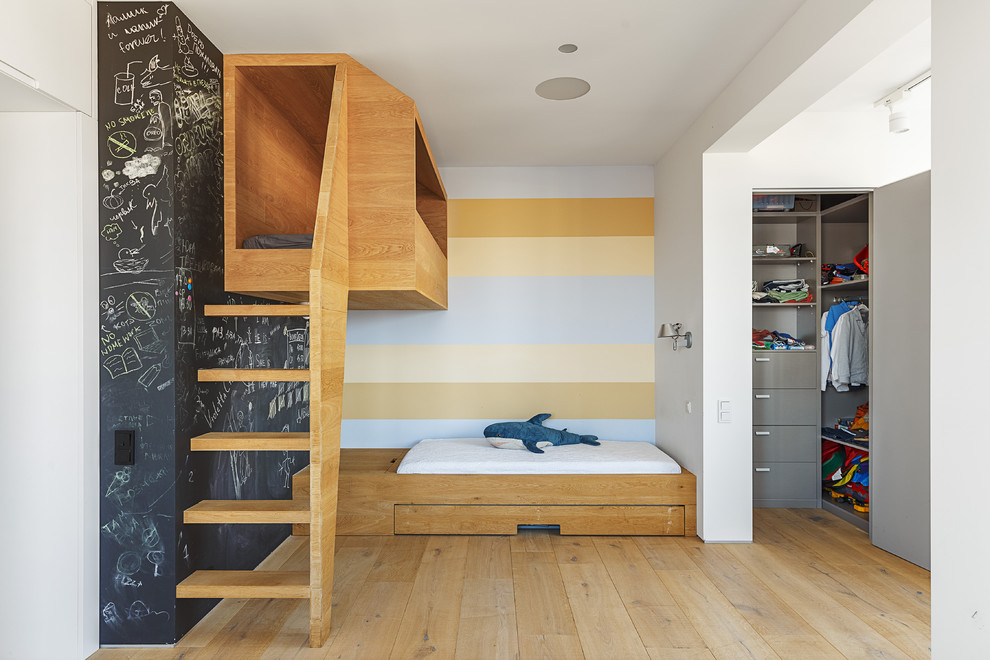 Imagen de dormitorio infantil de 4 a 10 años actual de tamaño medio con paredes blancas y suelo de madera clara