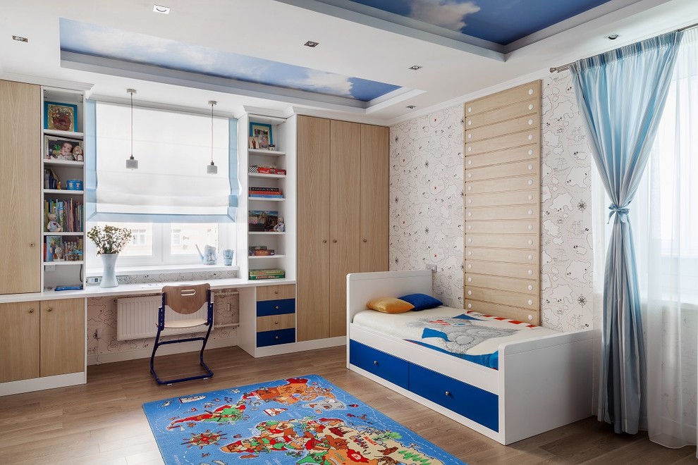 Esempio di una cameretta da bambino design con pareti beige e pavimento in legno massello medio