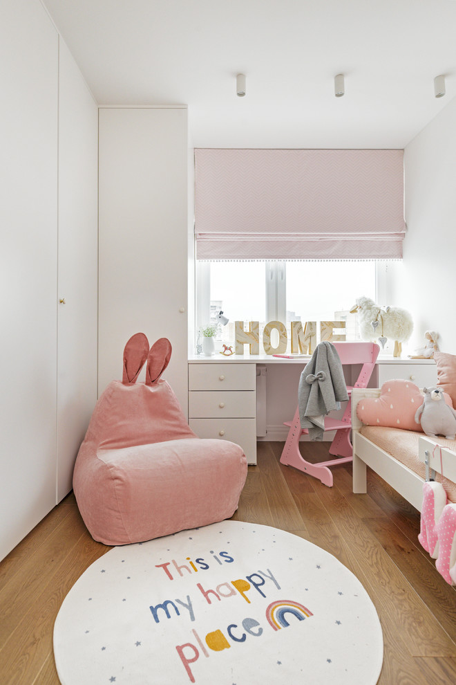 Bild på ett funkis barnrum kombinerat med sovrum, med vita väggar, mellanmörkt trägolv och brunt golv