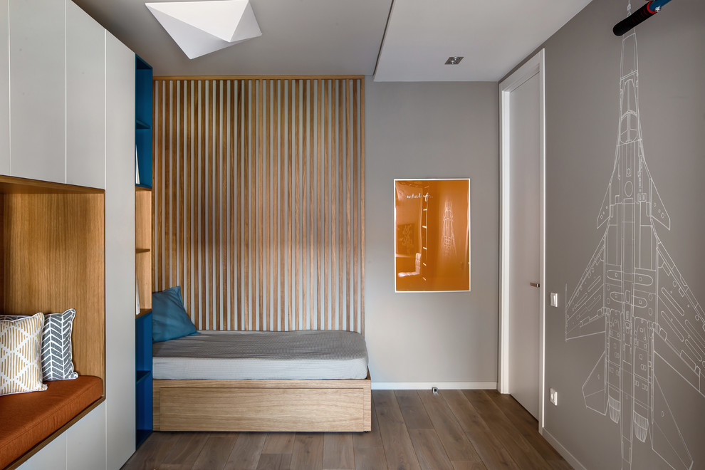 Aménagement d'une chambre d'enfant contemporaine de taille moyenne avec un mur gris et un sol en bois brun.