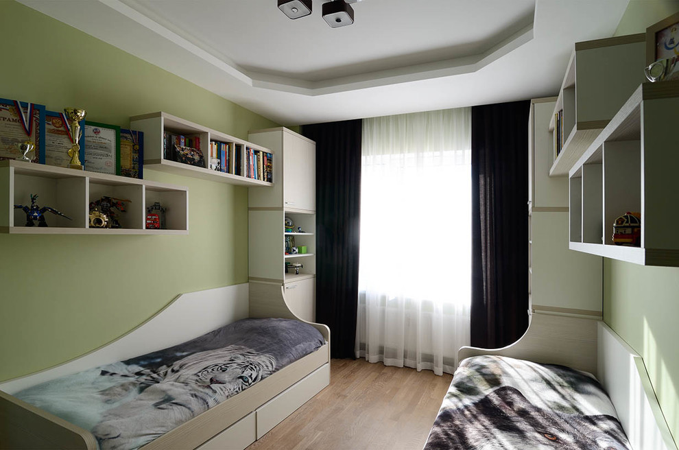 На фото: детская среднего размера в современном стиле с спальным местом, зелеными стенами, полом из ламината и коричневым полом для ребенка от 4 до 10 лет, мальчика с