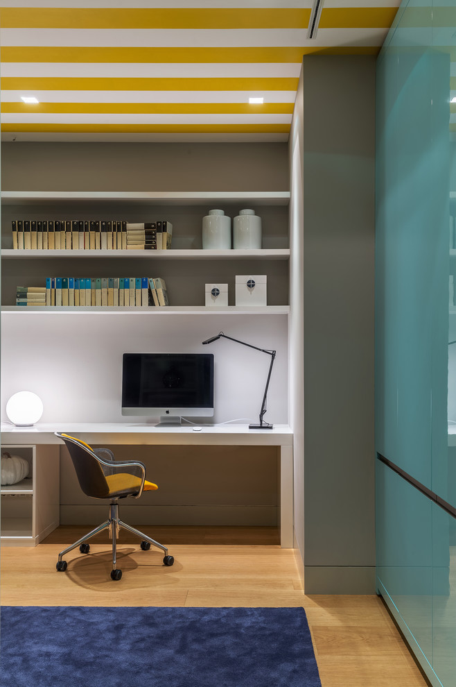Cette image montre une chambre d'enfant design avec un bureau, parquet clair, un sol beige et un mur blanc.