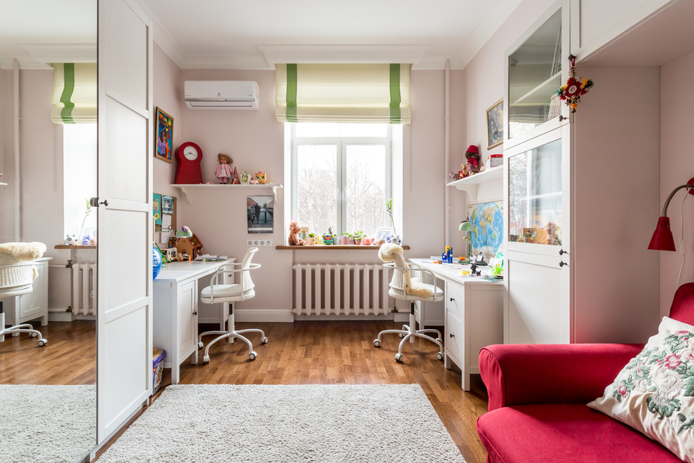 Diseño de habitación de niña tradicional de tamaño medio con escritorio, paredes rosas, suelo de madera en tonos medios y suelo marrón