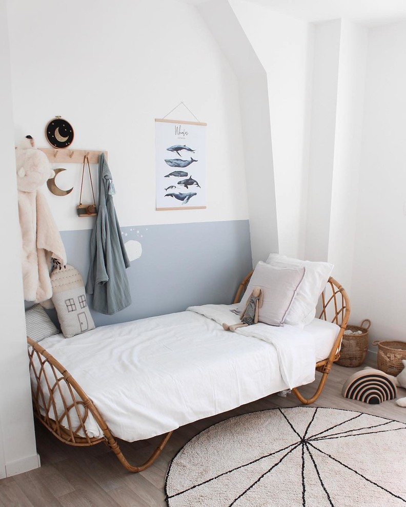Cette image montre une chambre d'enfant nordique avec un mur blanc, un sol en bois brun et un sol beige.