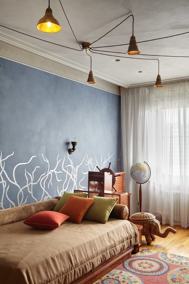 Aménagement d'une chambre d'enfant de 4 à 10 ans éclectique avec un mur bleu et un sol en bois brun.