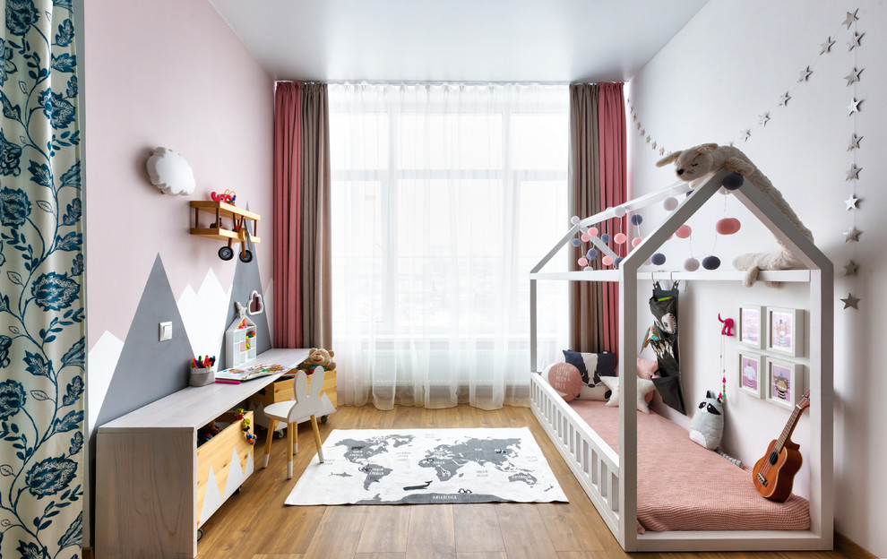 Scandi toddler’s room for girls in Other with white walls, medium hardwood flooring and brown floors.