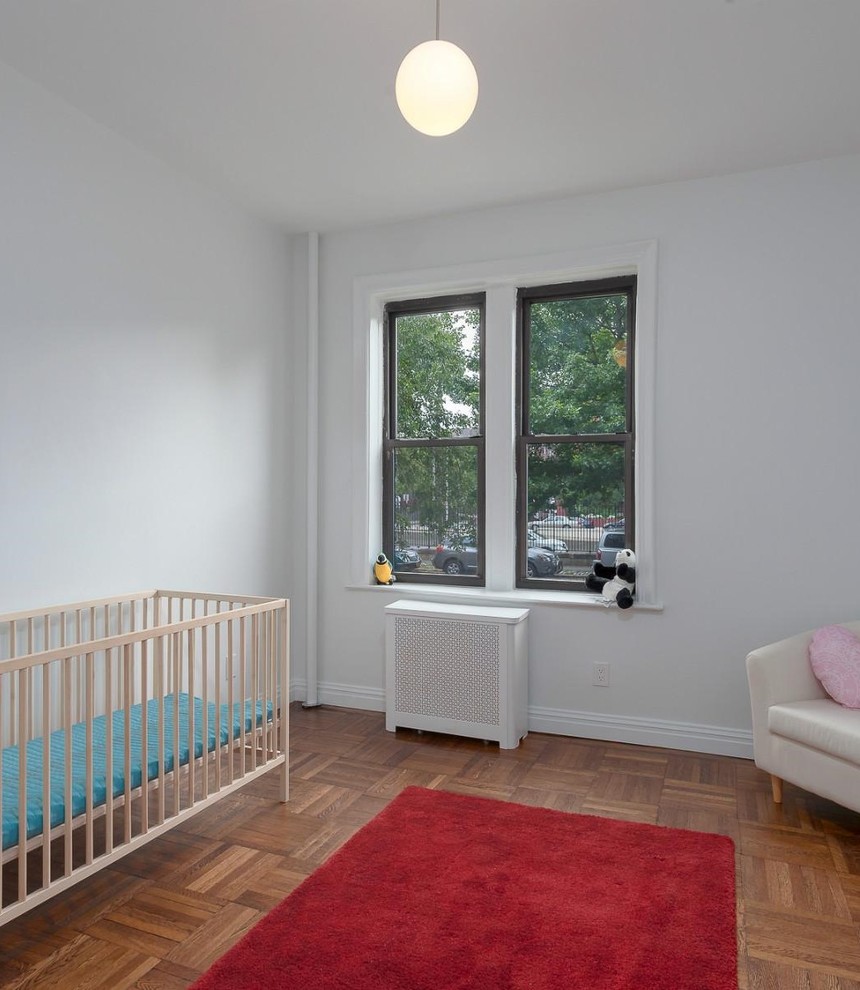 Idées déco pour une chambre de bébé classique avec un sol marron et un mur blanc.