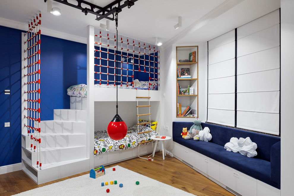 This is an example of a contemporary children’s room for boys in Other with blue walls and medium hardwood flooring.