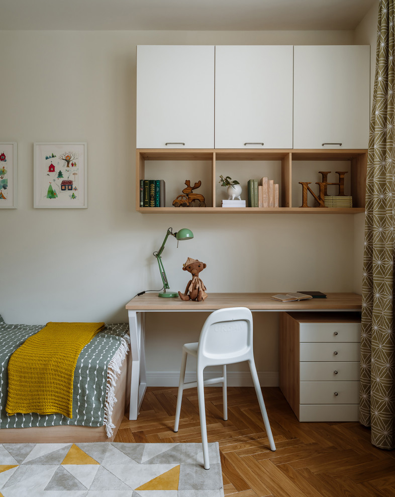 Cette image montre une chambre de garçon de 1 à 3 ans nordique de taille moyenne avec un bureau, un mur blanc, un sol en bois brun et un sol marron.