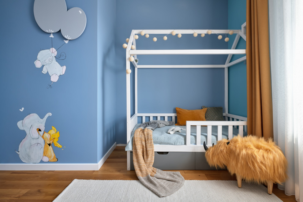 На фото: детская среднего размера в современном стиле с спальным местом, синими стенами и коричневым полом для ребенка от 4 до 10 лет, мальчика с