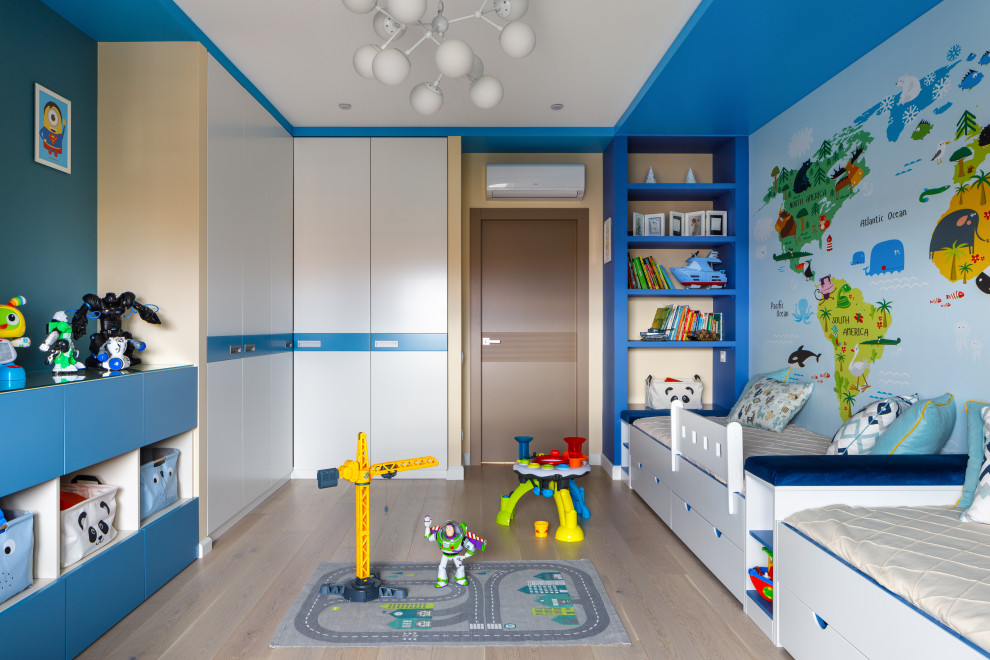 Imagen de habitación de niño de 4 a 10 años actual con paredes azules, suelo de madera clara y suelo beige