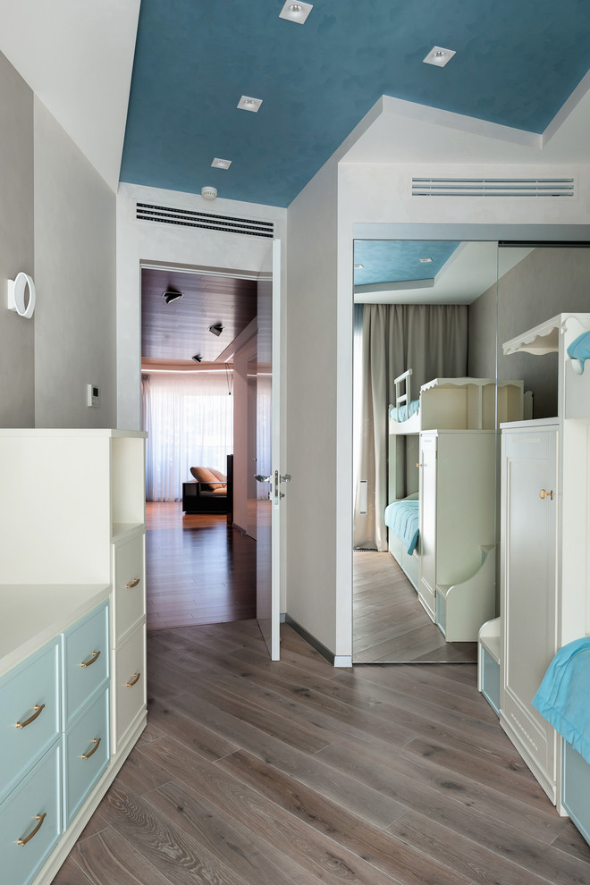 Cette photo montre une chambre d'enfant tendance de taille moyenne avec un mur blanc et un sol en bois brun.