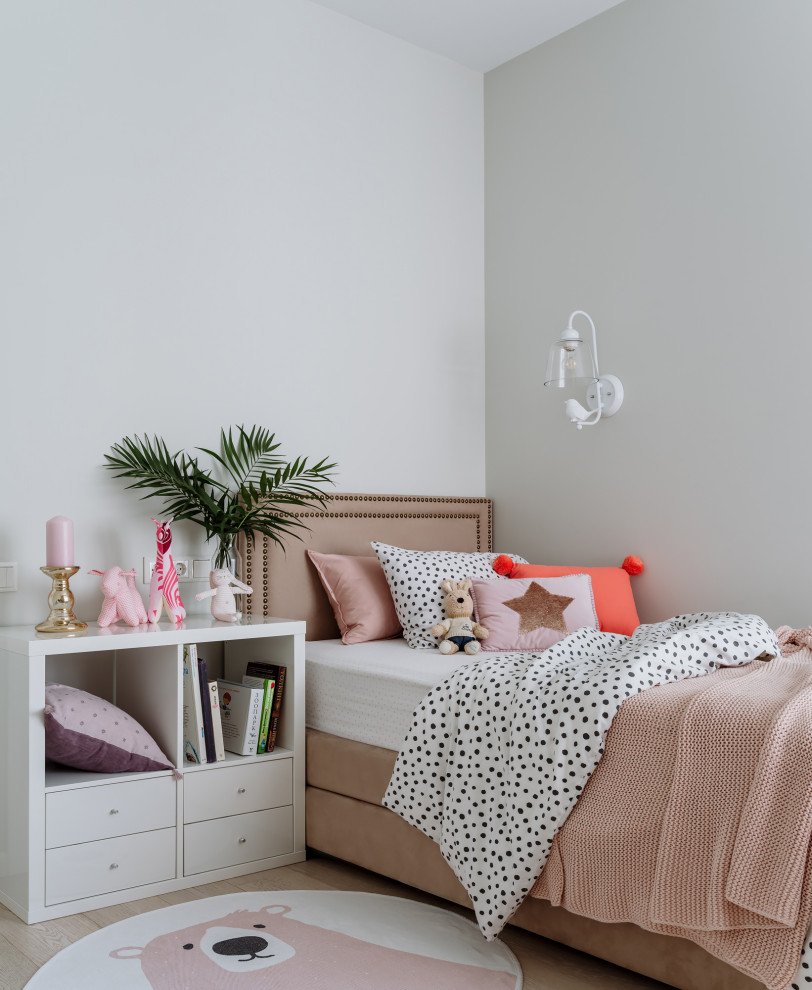 Diseño de dormitorio infantil actual de tamaño medio con paredes blancas, suelo de madera clara y suelo beige