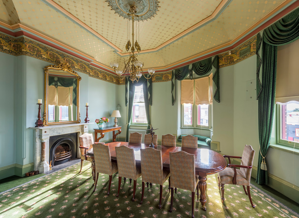 Réalisation d'une grande salle à manger victorienne avec un mur vert, moquette, une cheminée standard et un manteau de cheminée en pierre.