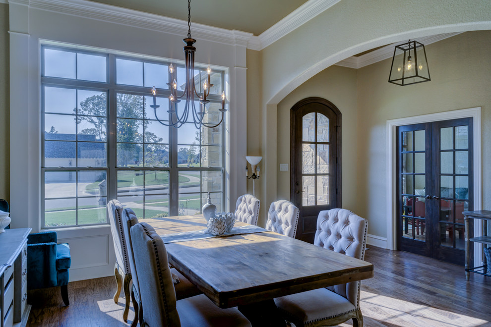 Cette image montre une grande salle à manger ouverte sur le salon traditionnelle avec un mur beige, un sol en bois brun et aucune cheminée.