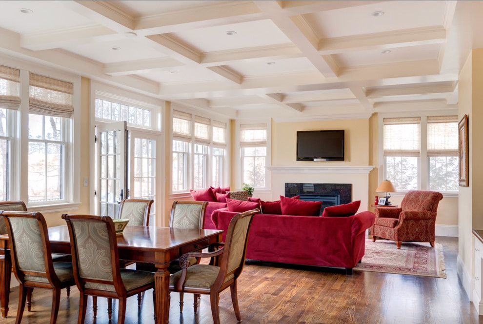 Cette image montre une grande salle à manger ouverte sur le salon traditionnelle avec un mur jaune et un sol en bois brun.
