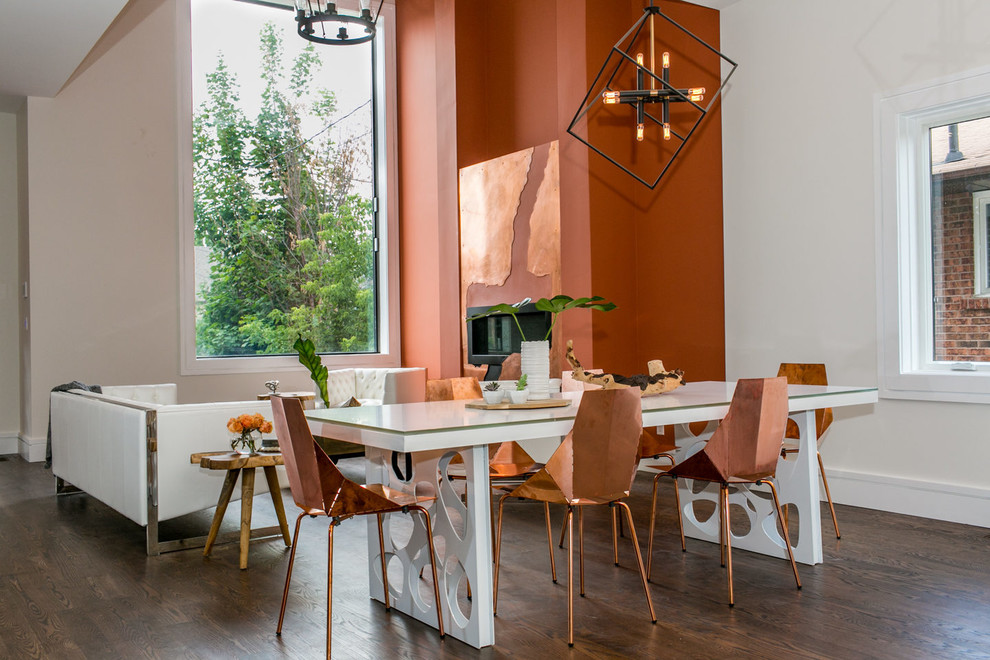 Immagine di una grande sala da pranzo aperta verso il soggiorno contemporanea con pareti arancioni e parquet scuro
