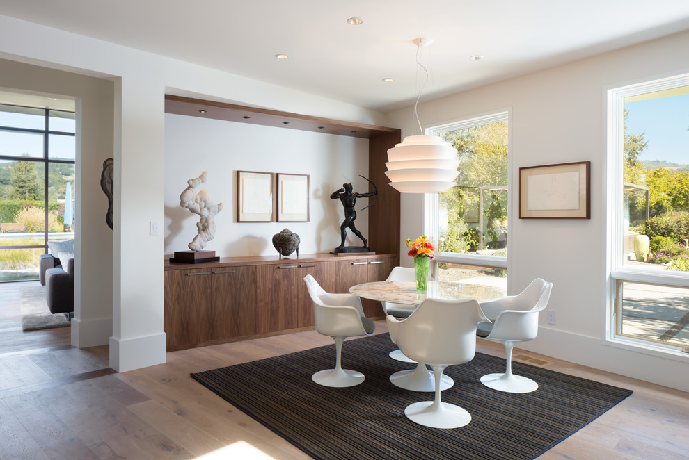 This is an example of a modern dining room in San Francisco with white walls and medium hardwood flooring.