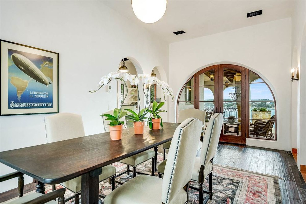 Large tuscan dark wood floor and brown floor enclosed dining room photo in Austin with white walls