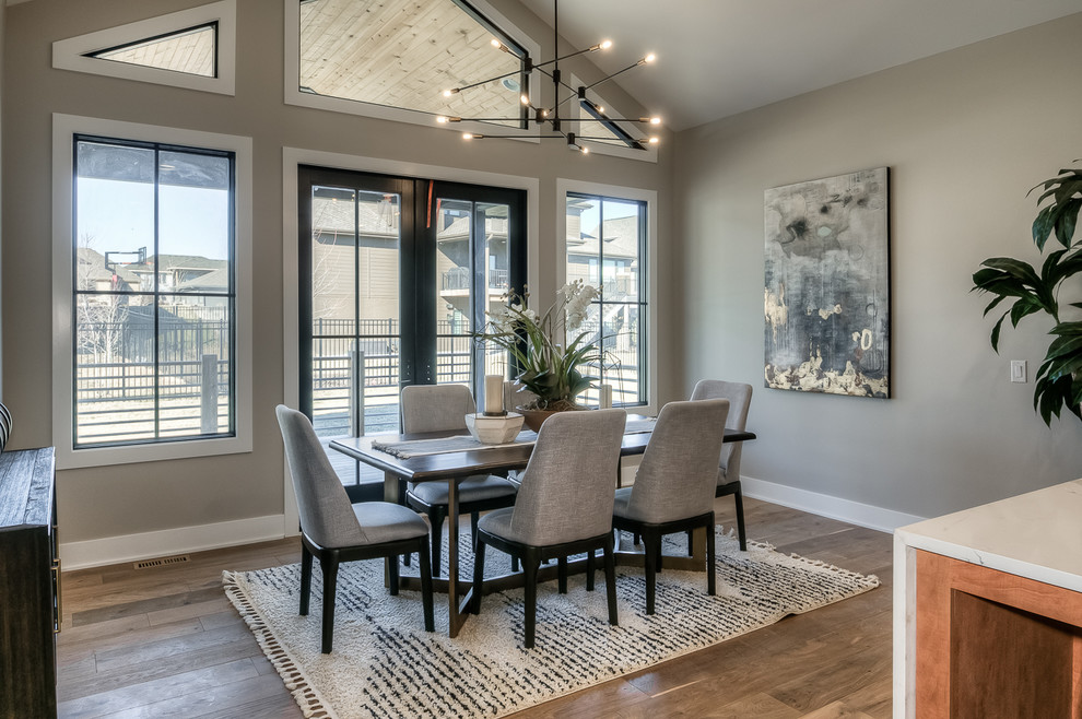 This is an example of a contemporary dining room in Omaha with grey walls, medium hardwood flooring and brown floors.