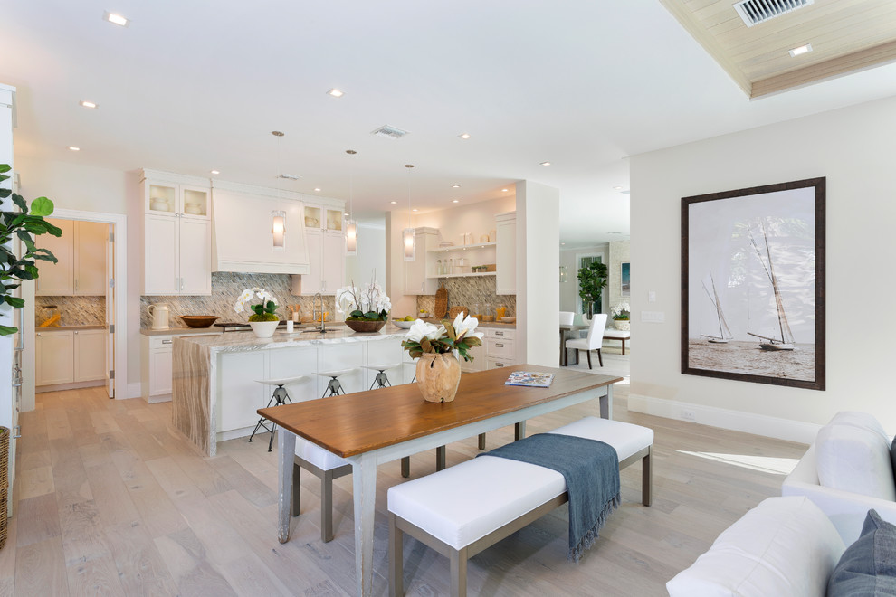 Foto di una sala da pranzo aperta verso il soggiorno costiera con pareti beige, parquet chiaro e pavimento beige