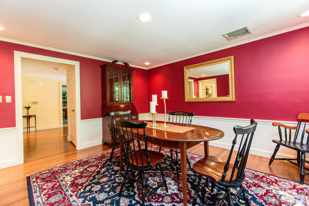 Cette image montre une salle à manger traditionnelle fermée et de taille moyenne avec un mur rouge et un sol en bois brun.