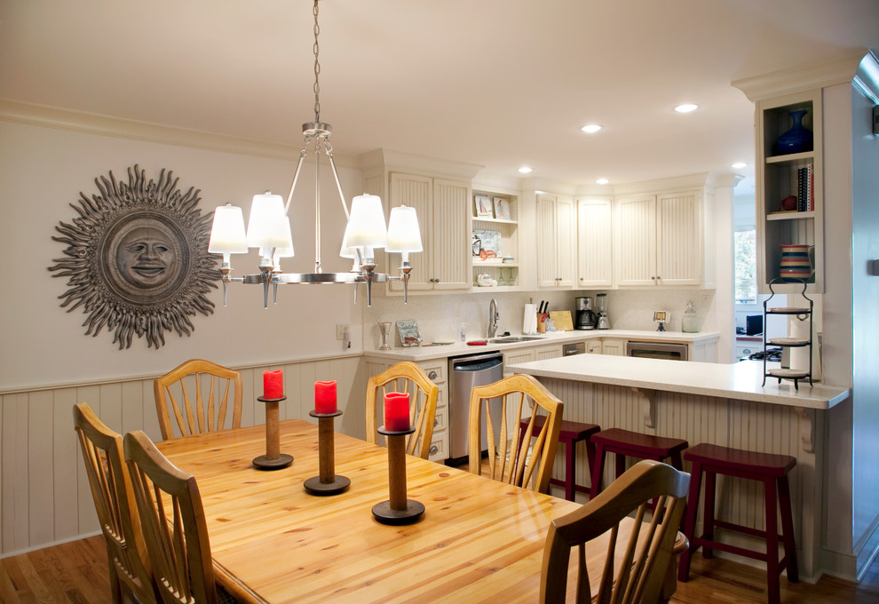 Cette image montre une salle à manger ouverte sur la cuisine ethnique avec un mur blanc et un sol en bois brun.