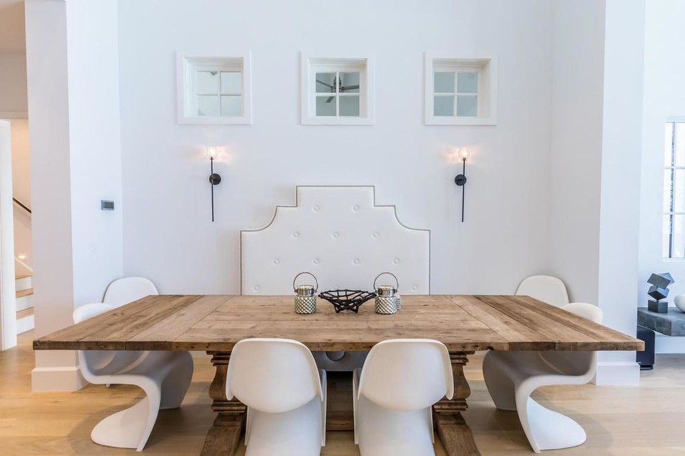 Imagen de comedor costero con paredes blancas, suelo de madera clara y suelo beige