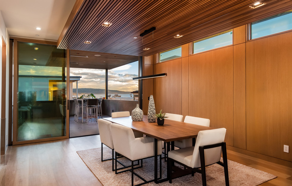 Foto di una grande sala da pranzo aperta verso la cucina minimal con pareti marroni, pavimento in legno massello medio, pavimento marrone, soffitto in legno e pareti in legno