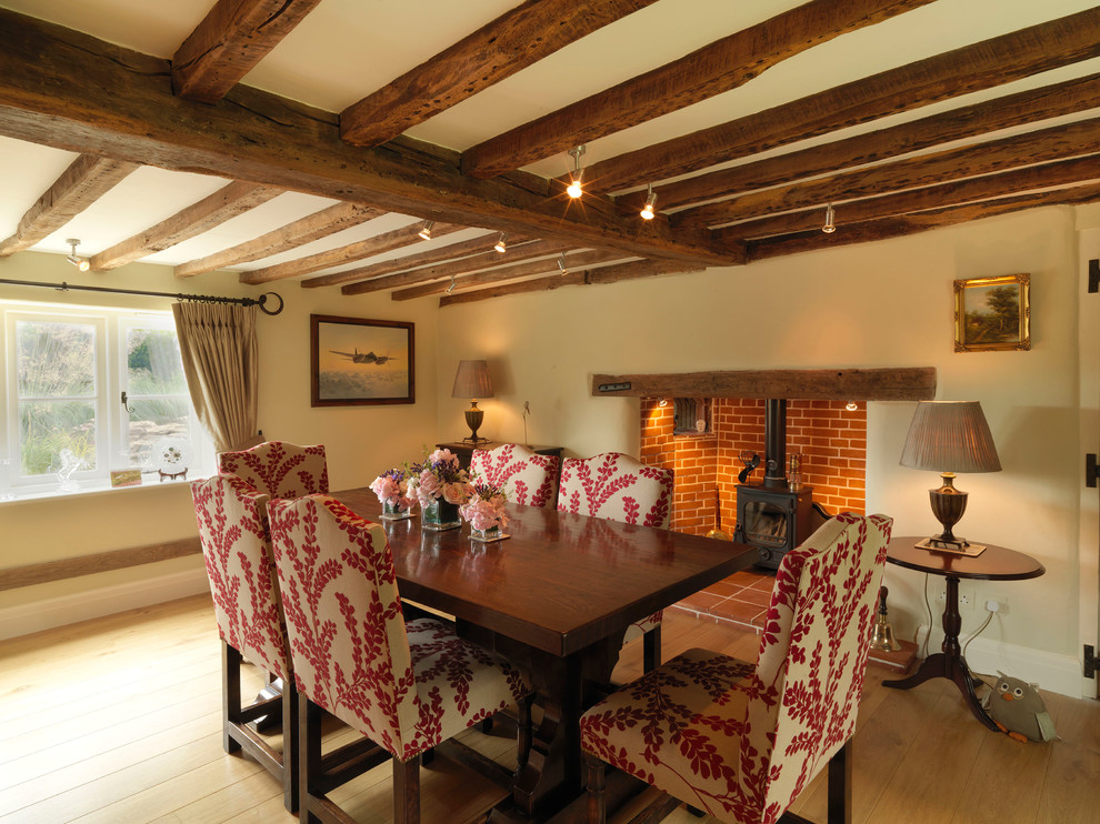 Exemple d'une grande salle à manger nature fermée avec un mur beige, un sol en bois brun, un poêle à bois et éclairage.