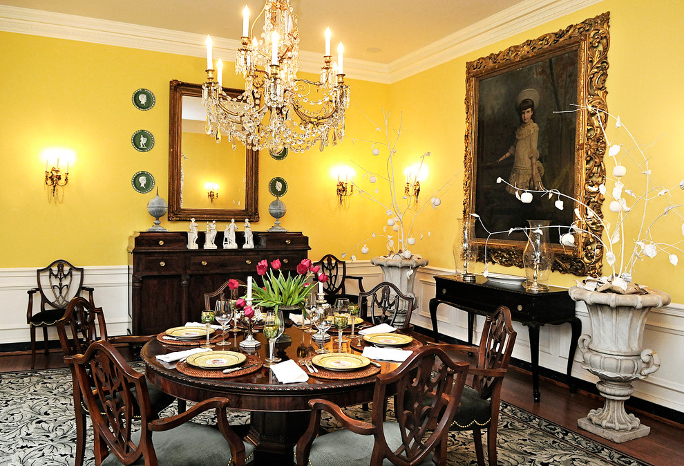 Cette image montre une grande salle à manger ouverte sur la cuisine traditionnelle avec un mur jaune, parquet foncé, aucune cheminée et un sol marron.