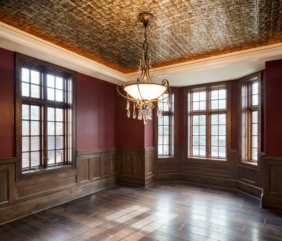 Aménagement d'une salle à manger classique avec parquet foncé, un sol marron et un mur rouge.