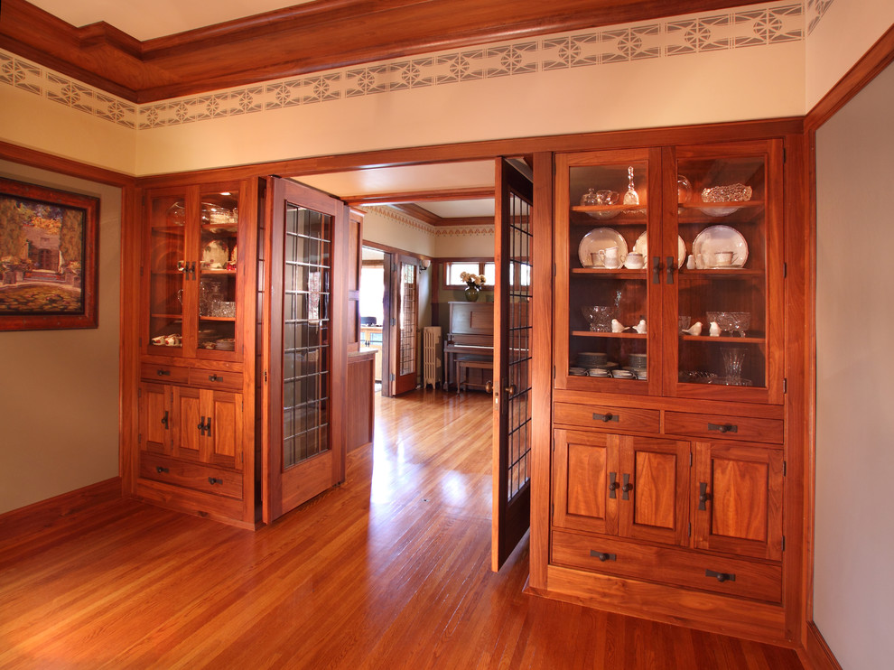 Cette photo montre une grande salle à manger craftsman fermée avec un mur gris et un sol en bois brun.