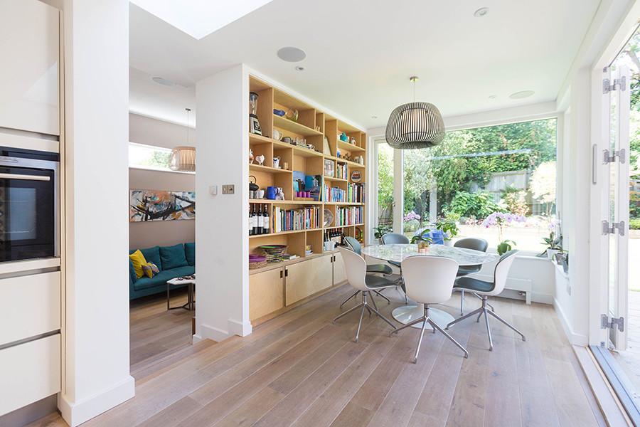 Medium sized contemporary open plan dining room in London with white walls, light hardwood flooring and beige floors.